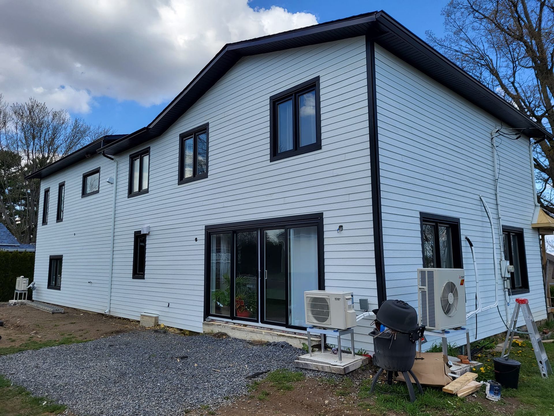 Une grande maison blanche avec des garnitures noires est en cours de rénovation.