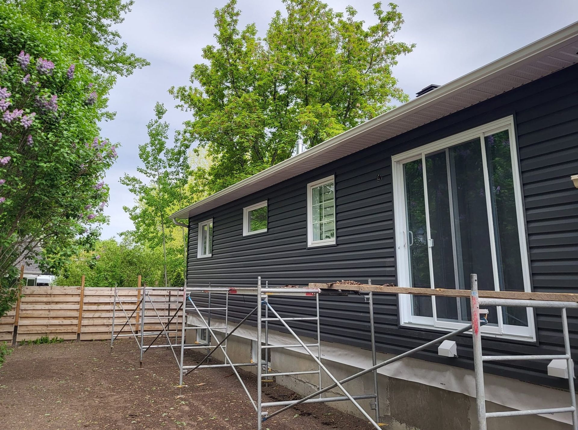 Une maison noire avec un échafaudage devant elle est en train d'être peinte.