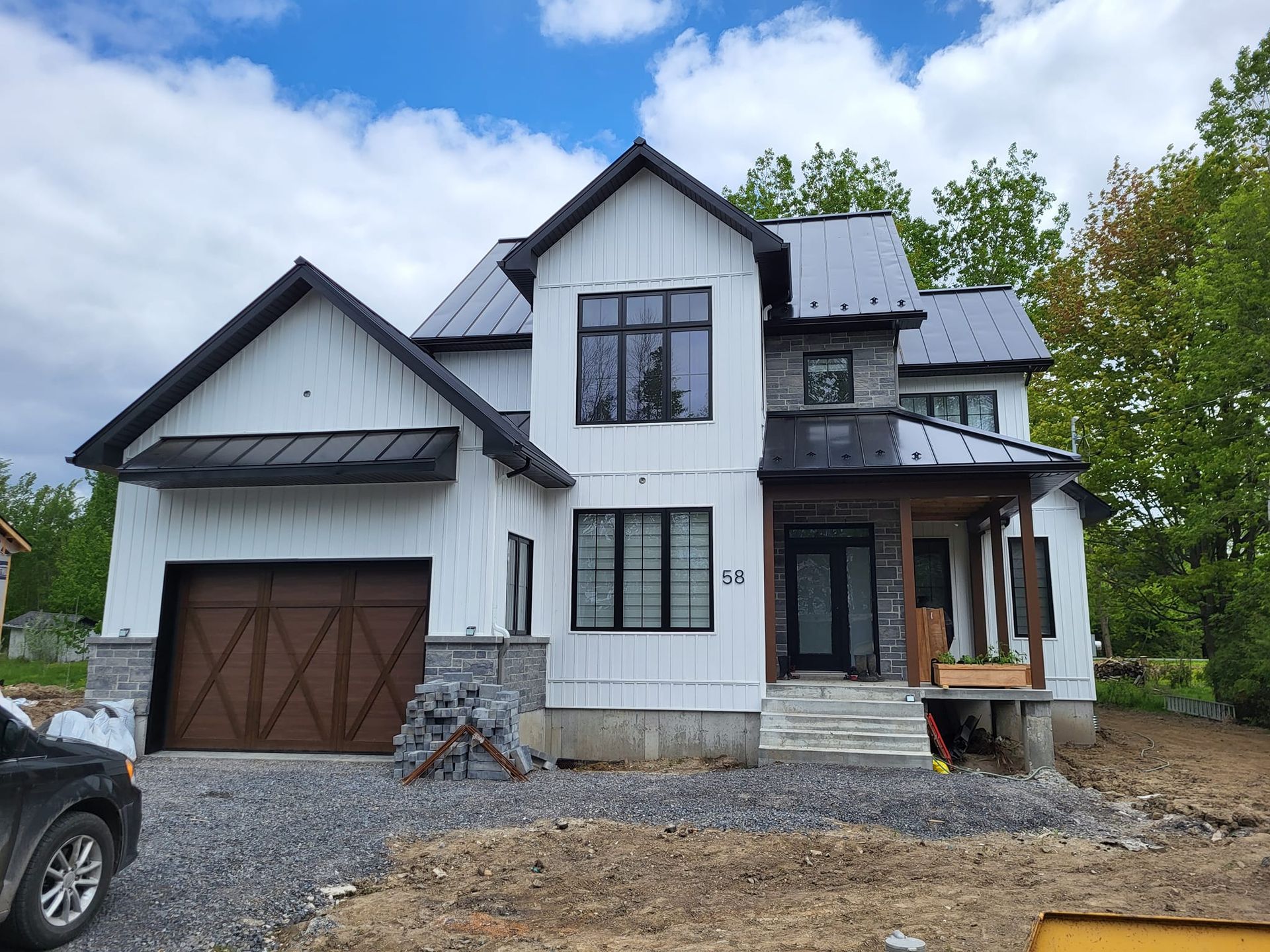 Une grande maison blanche avec un toit noir est en construction.