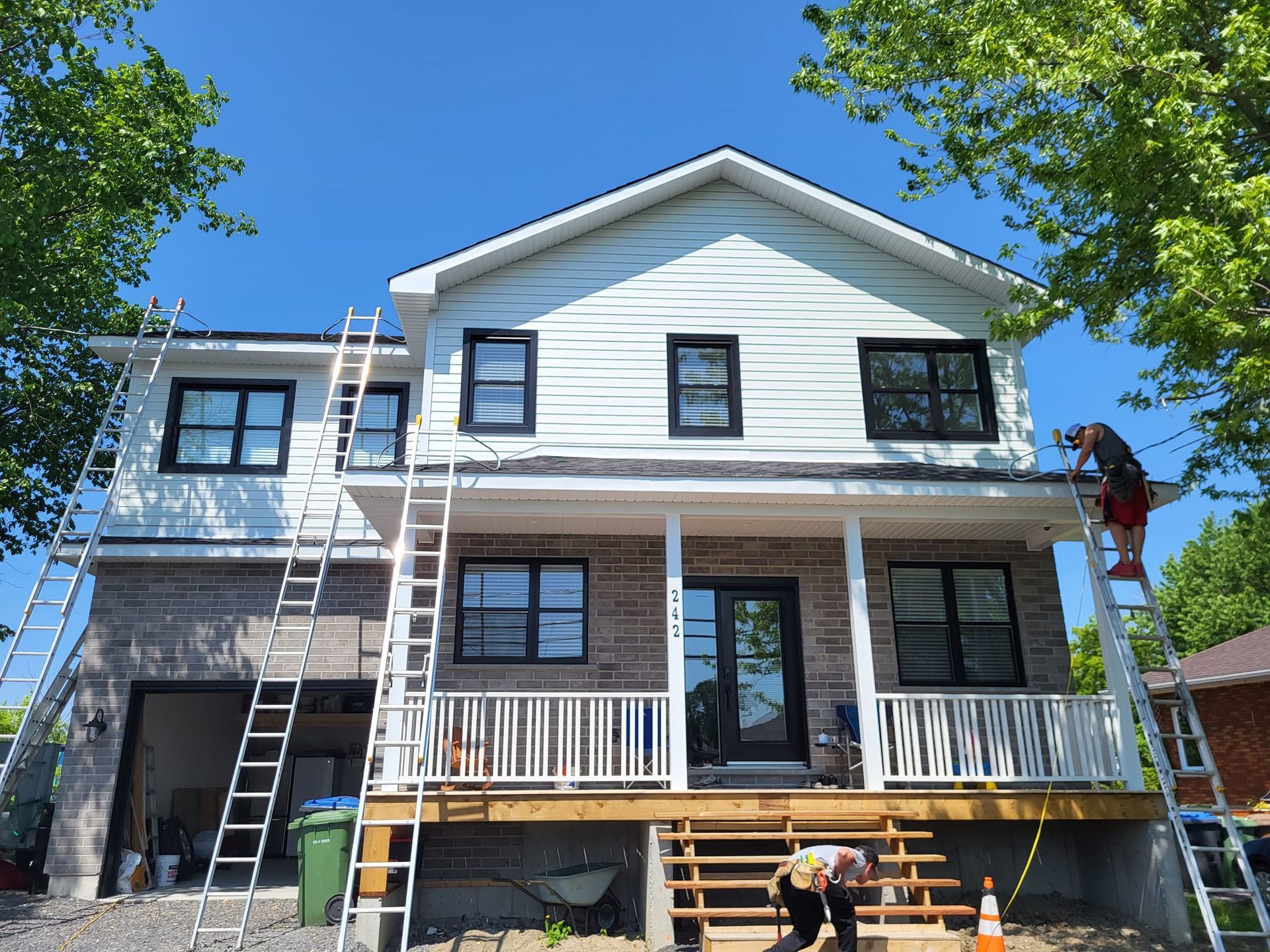 Un homme sur une échelle travaille sur le toit d'une maison.