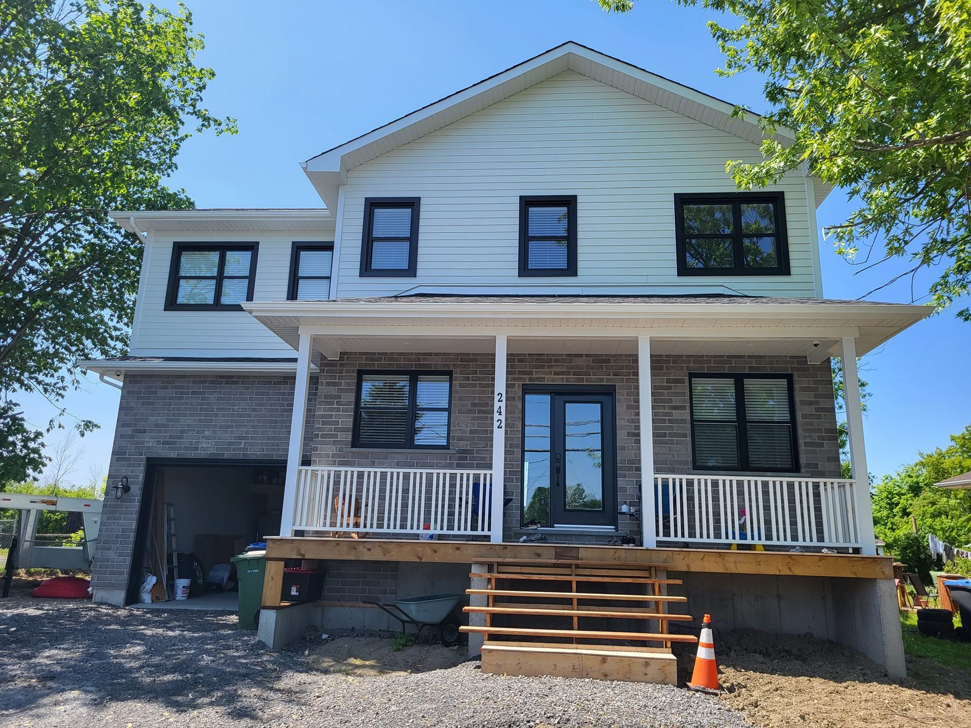 Une grande maison blanche avec un porche et des escaliers est en cours de construction.