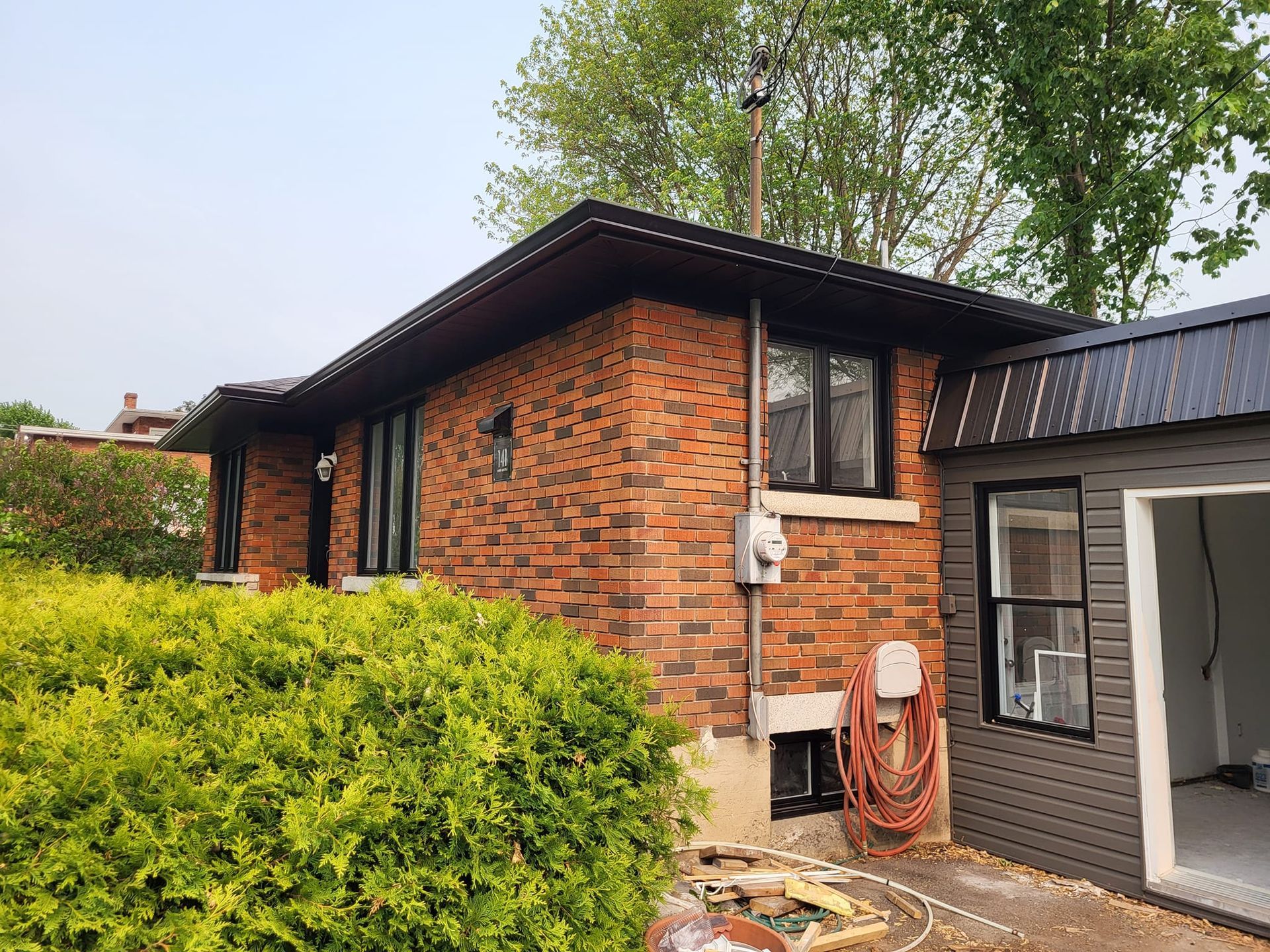 Une maison en briques avec un toit noir et un garage dans l'arrière-cour.