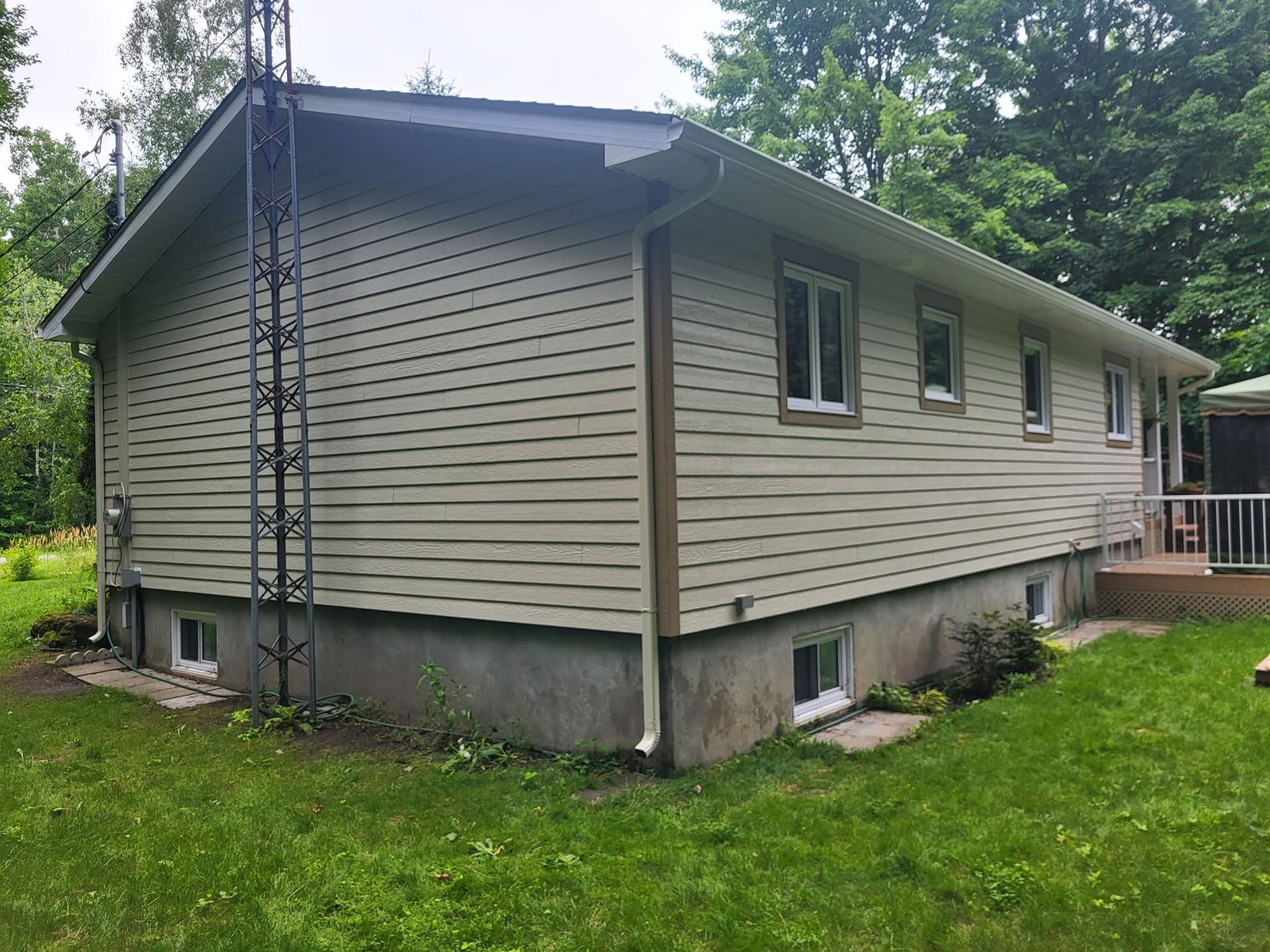 Une maison avec une échelle sur le côté est située au sommet d'un champ vert luxuriant.