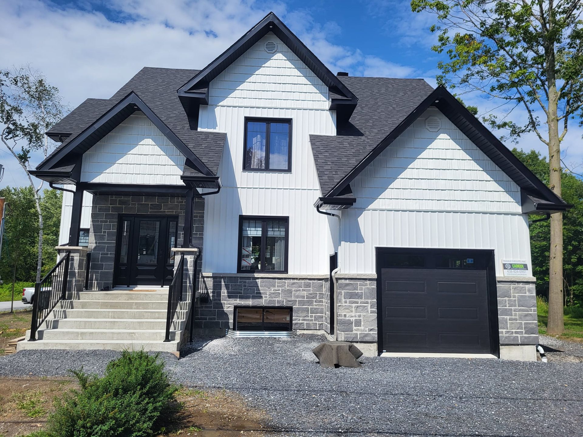 Une grande maison blanche et noire avec une porte de garage noire.