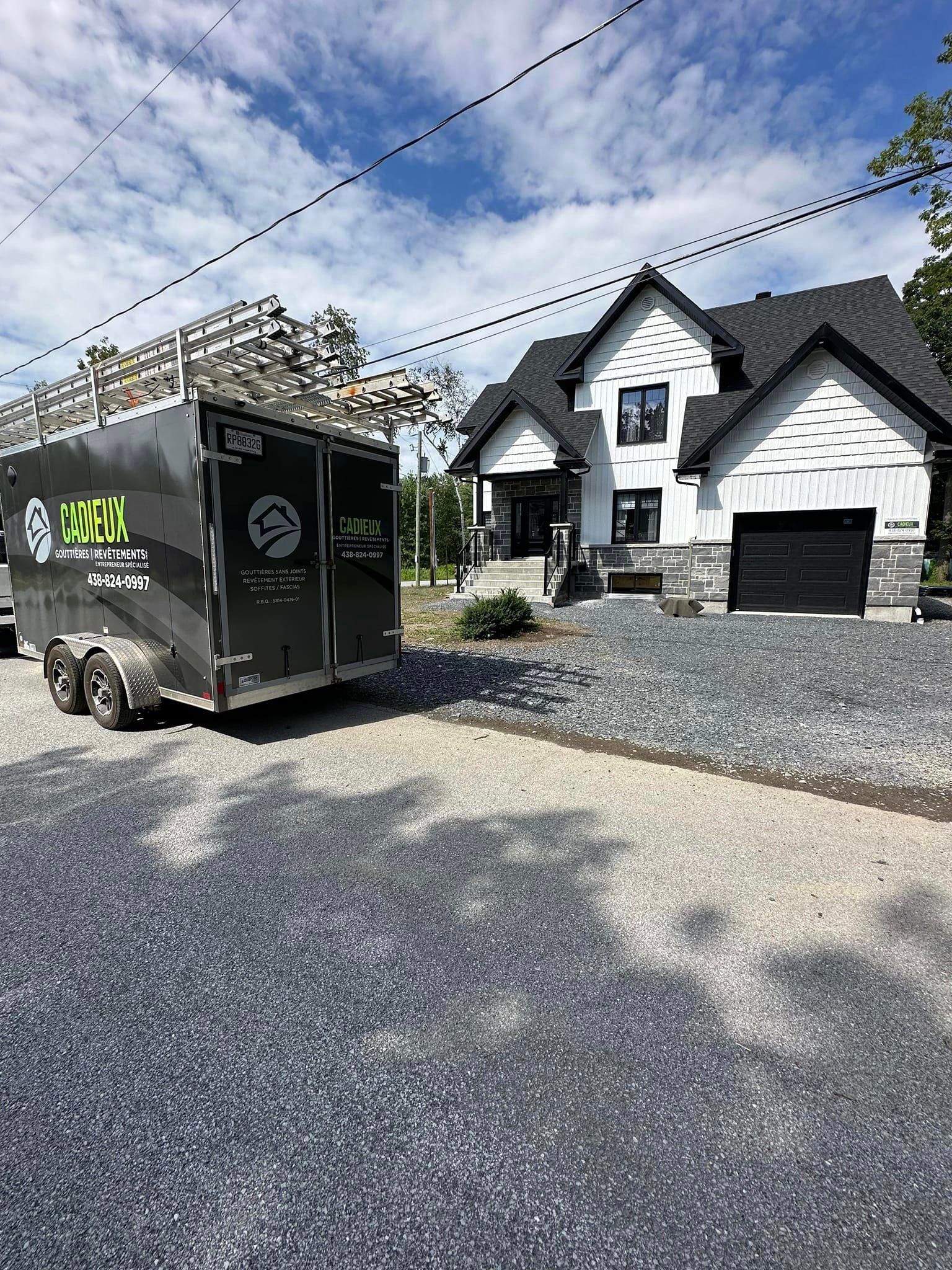 Une remorque est garée devant une grande maison.