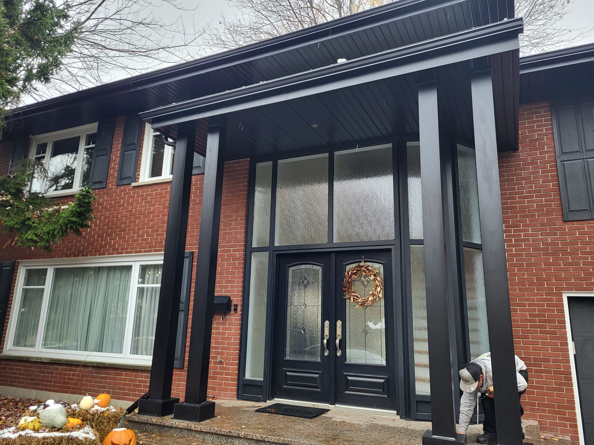 Une grande maison en briques avec un porche noir et une couronne sur la porte.