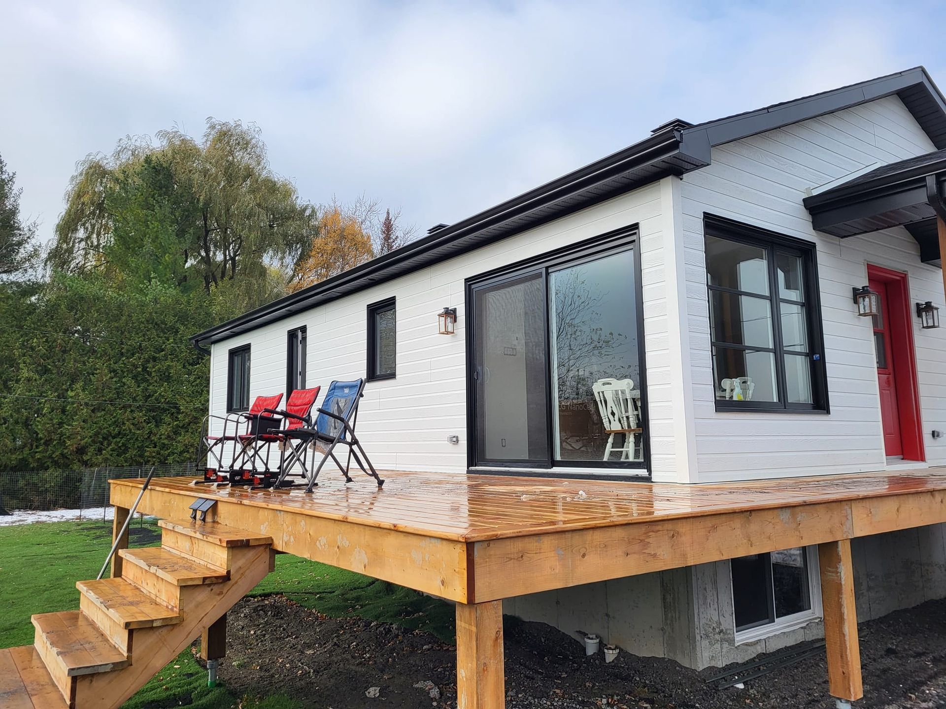 Une maison blanche avec une terrasse en bois et des escaliers devant.