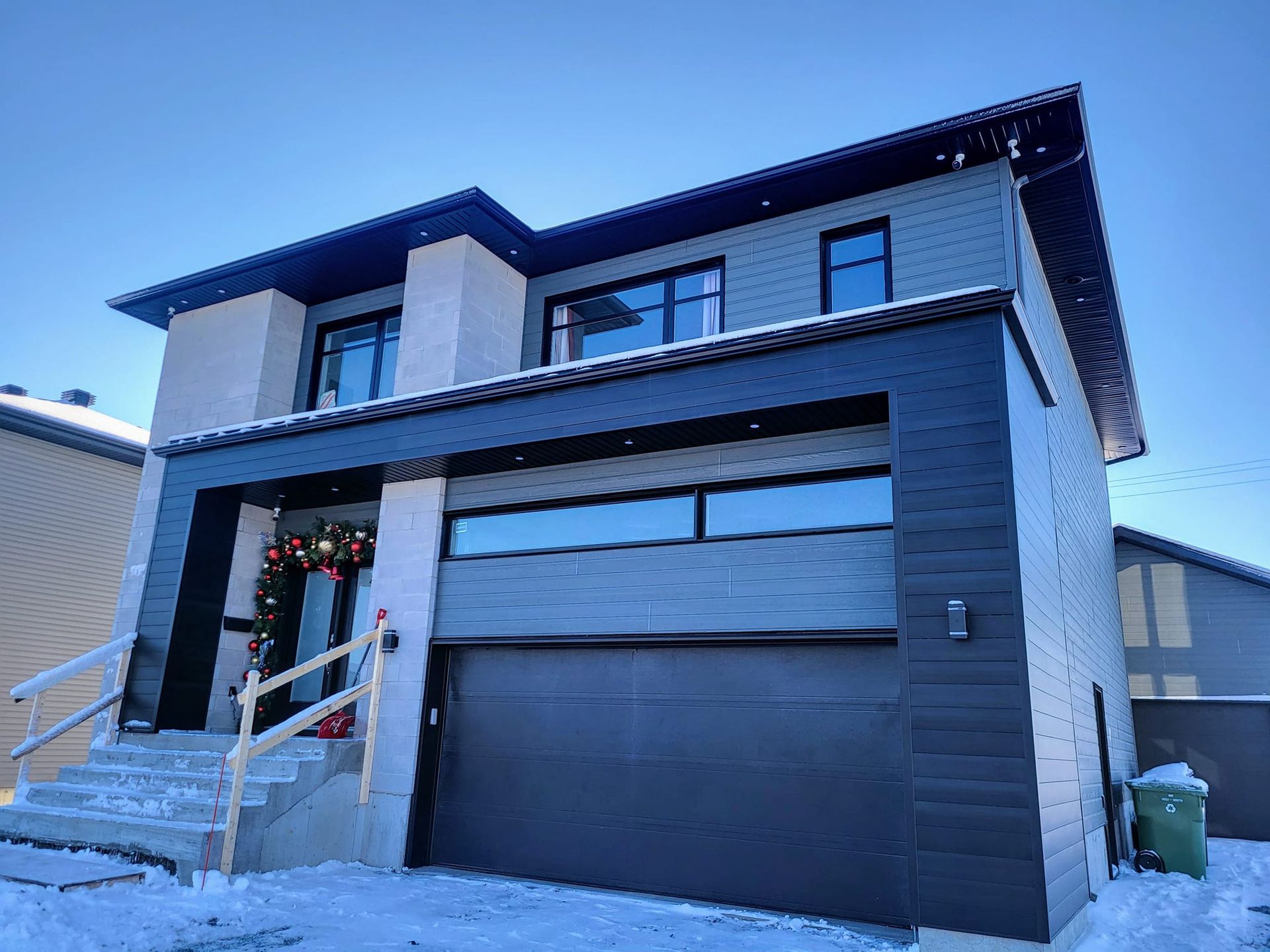 Une grande maison avec un garage et des escaliers dans la neige.
