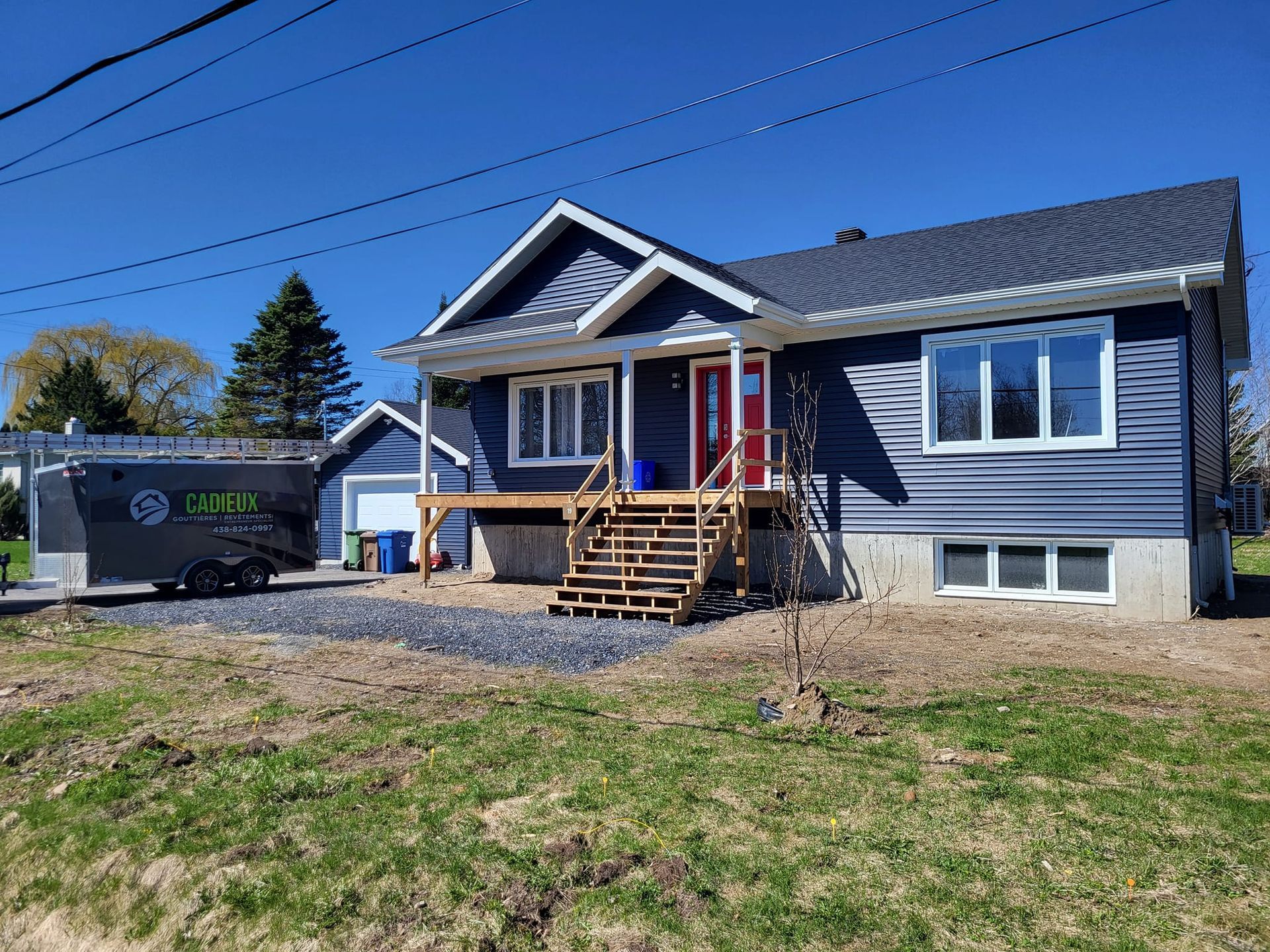 Une maison bleue avec une caravane garée devant.