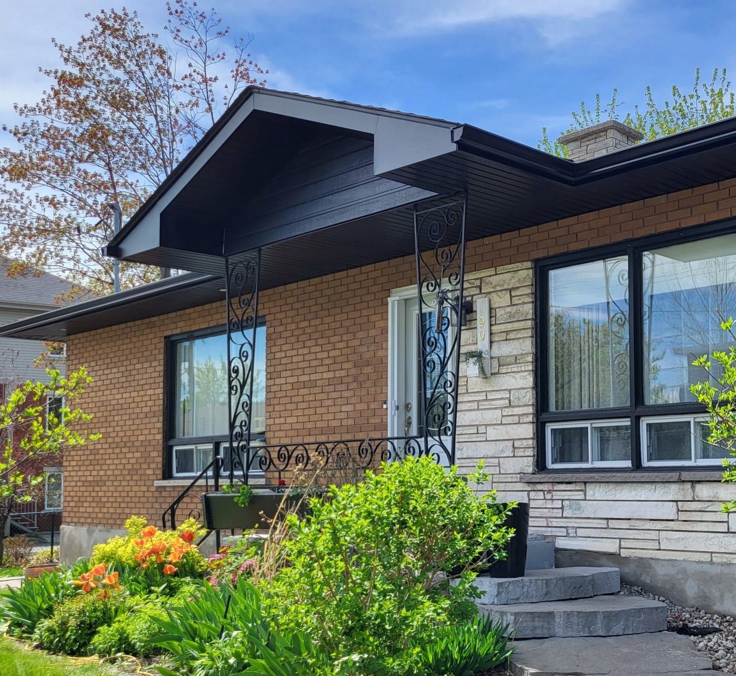 Une maison en briques avec un toit noir et de nombreuses fenêtres