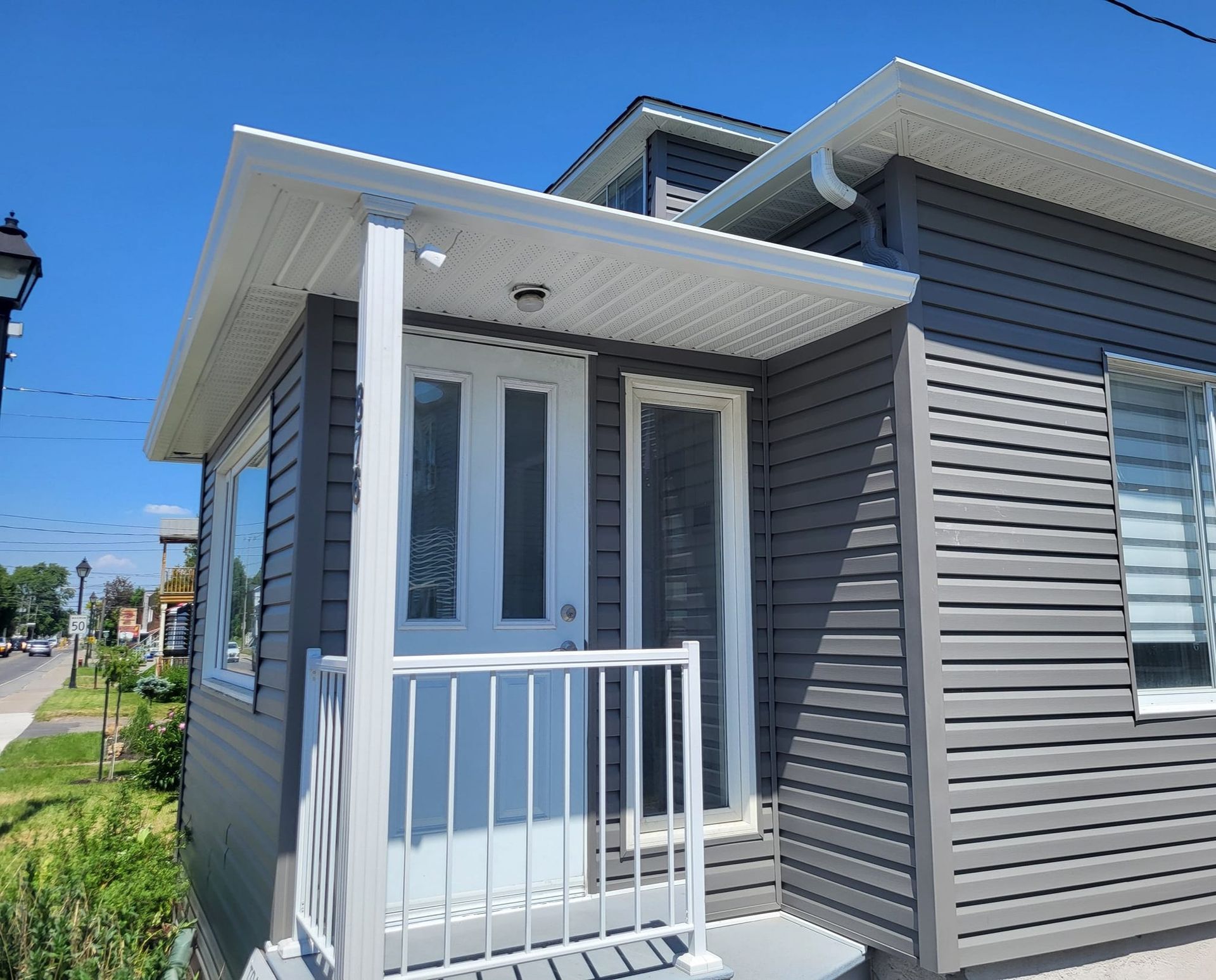 Une petite maison avec un porche et des escaliers par une journée ensoleillée.
