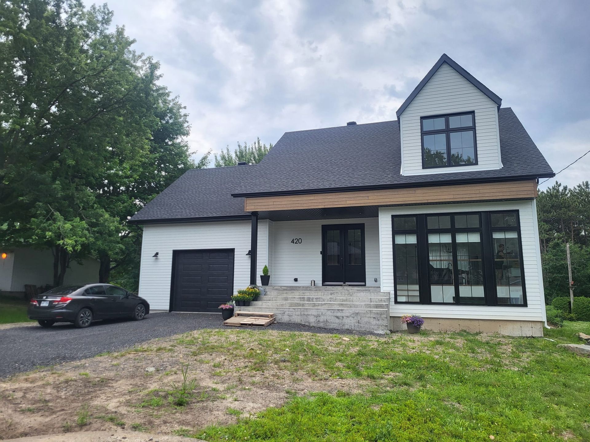 Une maison blanche avec une voiture noire garée devant.