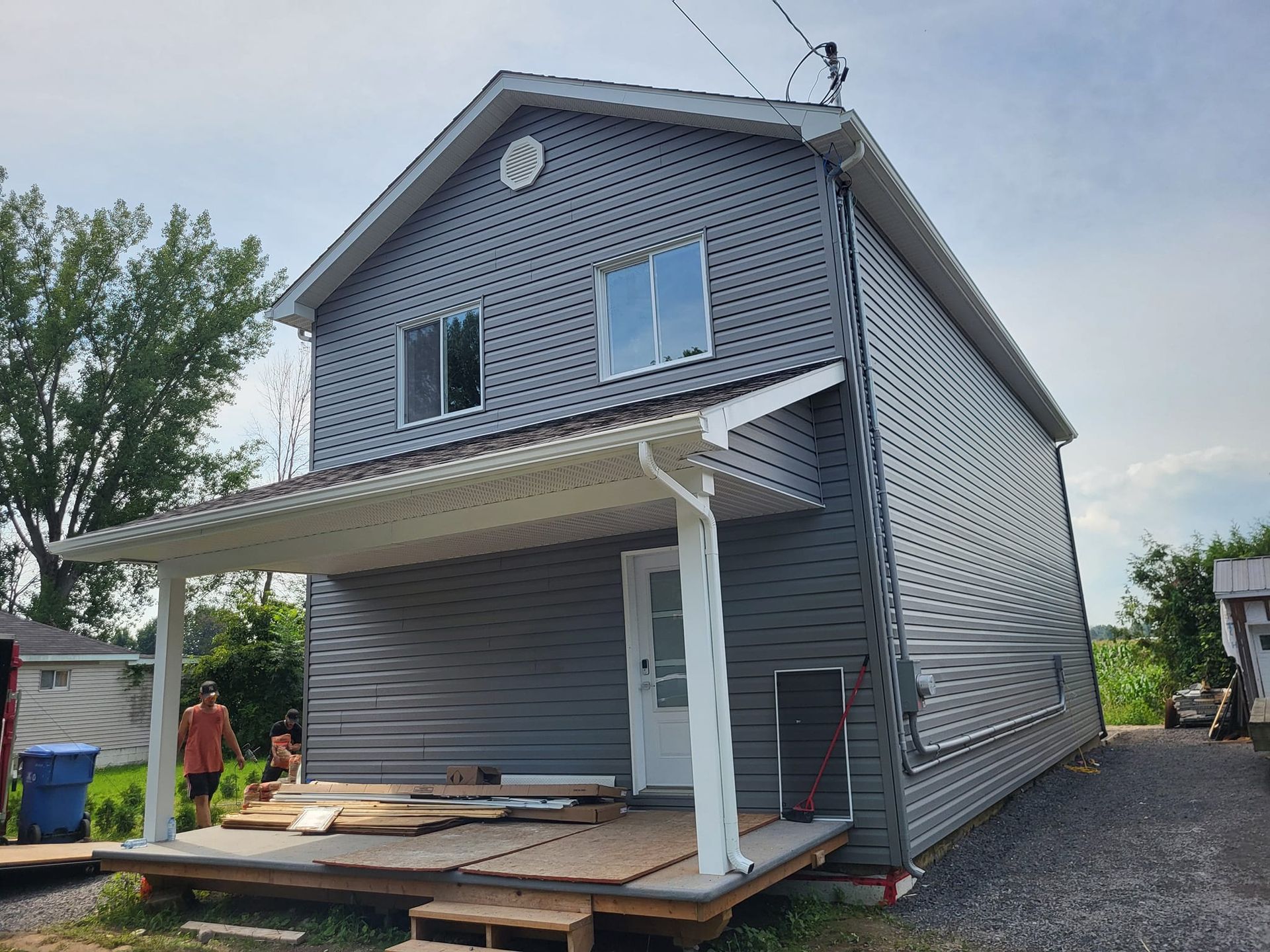 Une maison grise avec un porche blanc est en construction