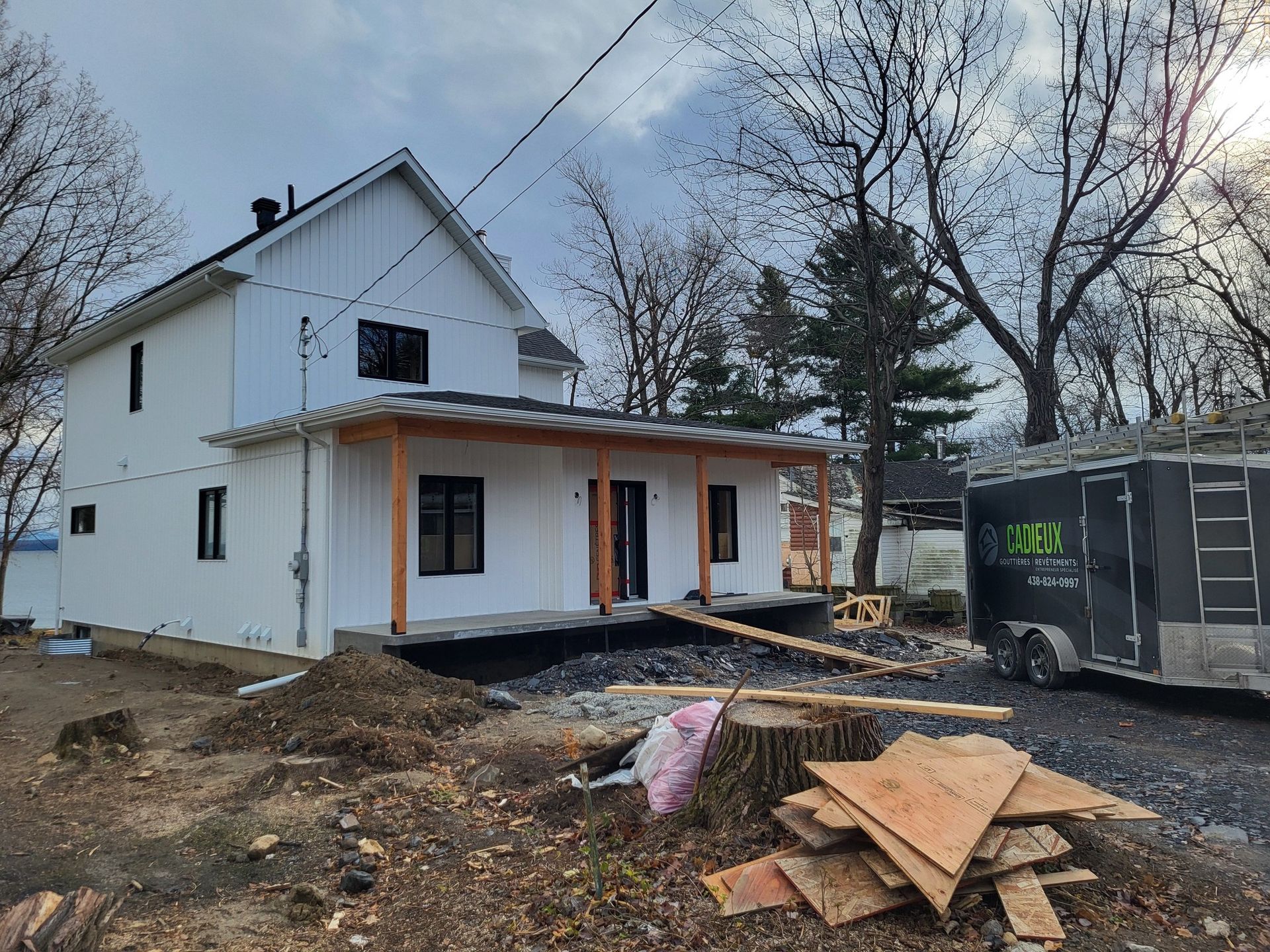 Une maison blanche en construction avec une caravane garée devant.