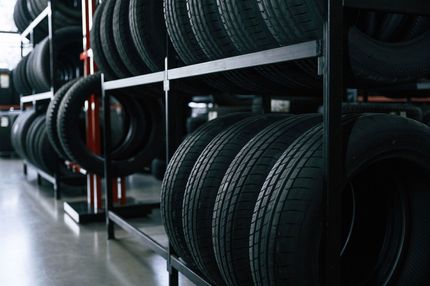 Black car tires stacked on metal shelves in a storage room.