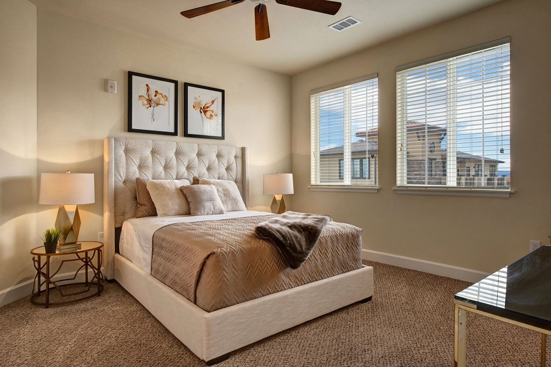 Bedroom with bed, lamps, artwork, and windows, beige and brown tones.