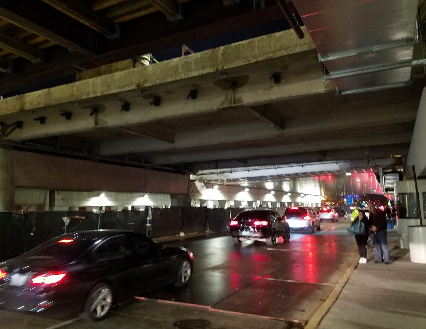 A car is parked under a bridge at night