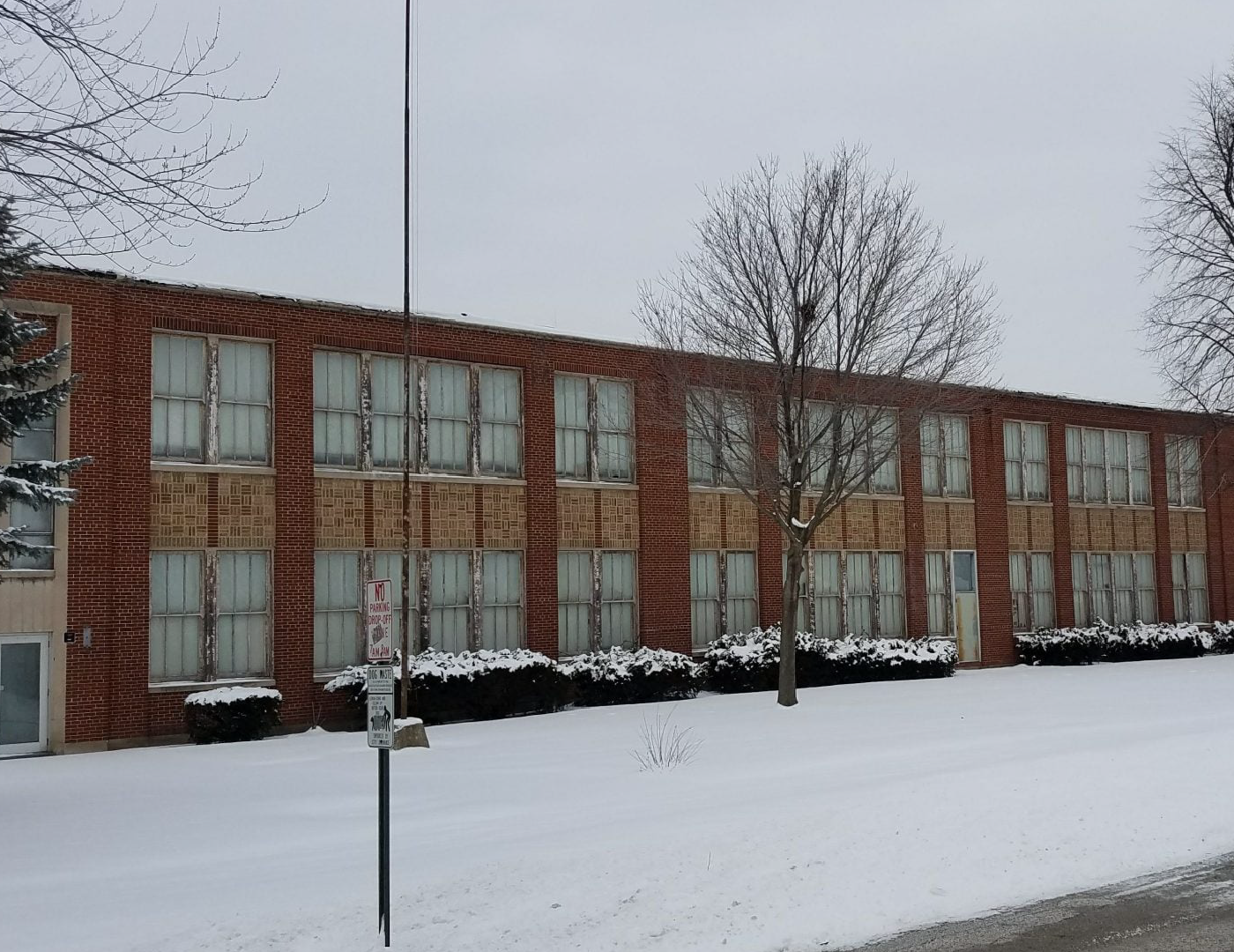 A large brick building with a lot of windows is covered in snow