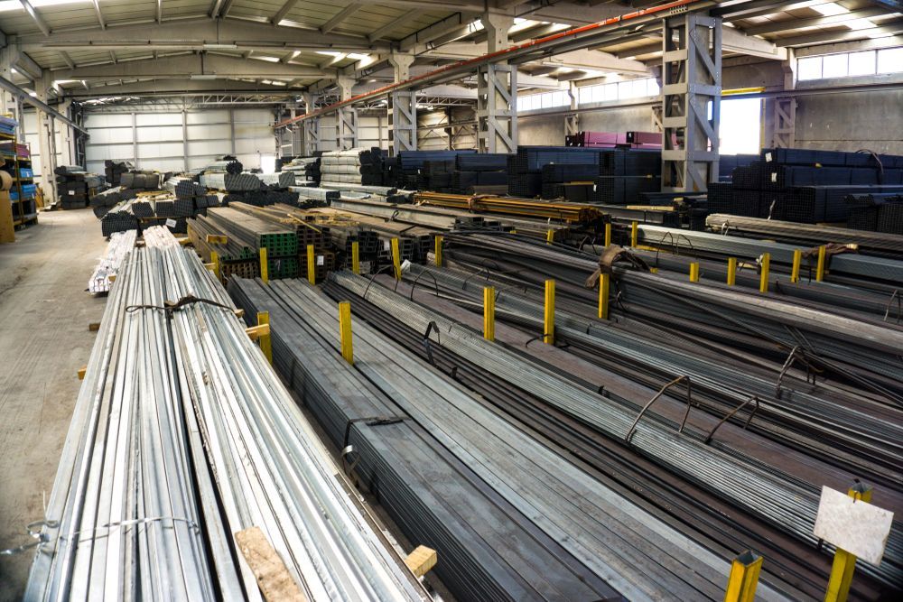 Architectural salvage materials stored in warehouse interior with steel pipes, chrome profiles, and construction supplies for reuse.