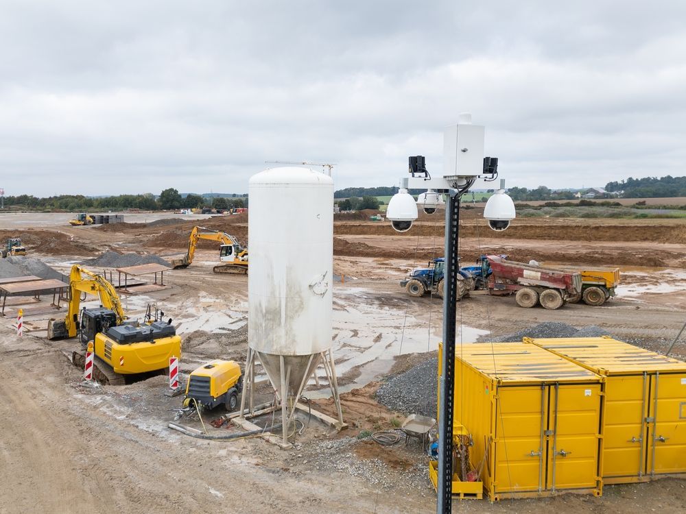 Mobilization phase with construction site protected with video technology, fencing, equipment staging, and initial setup in progress