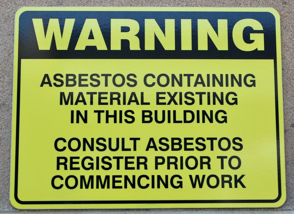 NESHAP asbestos warning sign posted on building indicating presence of hazardous materials