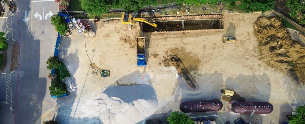 Tank removal at fuel station site with excavator and trucks excavating underground gas tanks