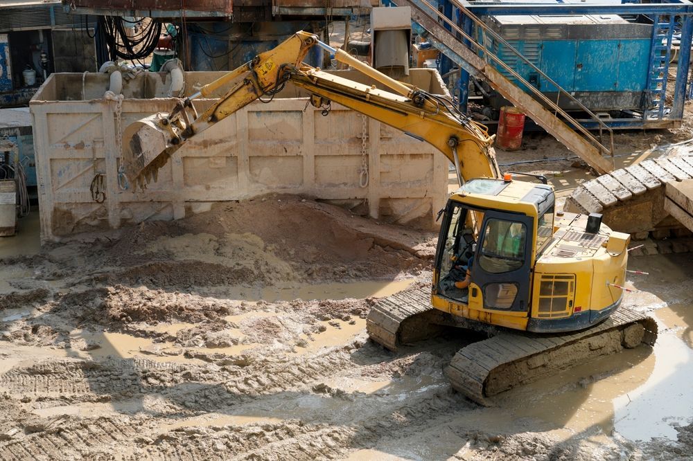 Zone of influence with heavy machinery moving earth near surrounding structures at active construction site