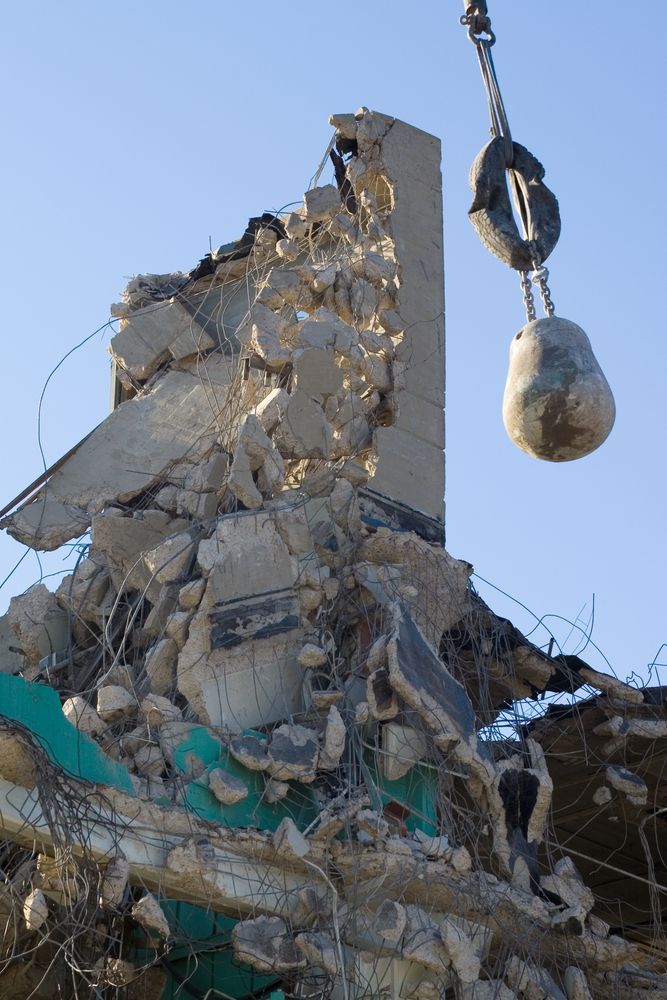 A large pile of rubble is being demolished by a wrecking ball.