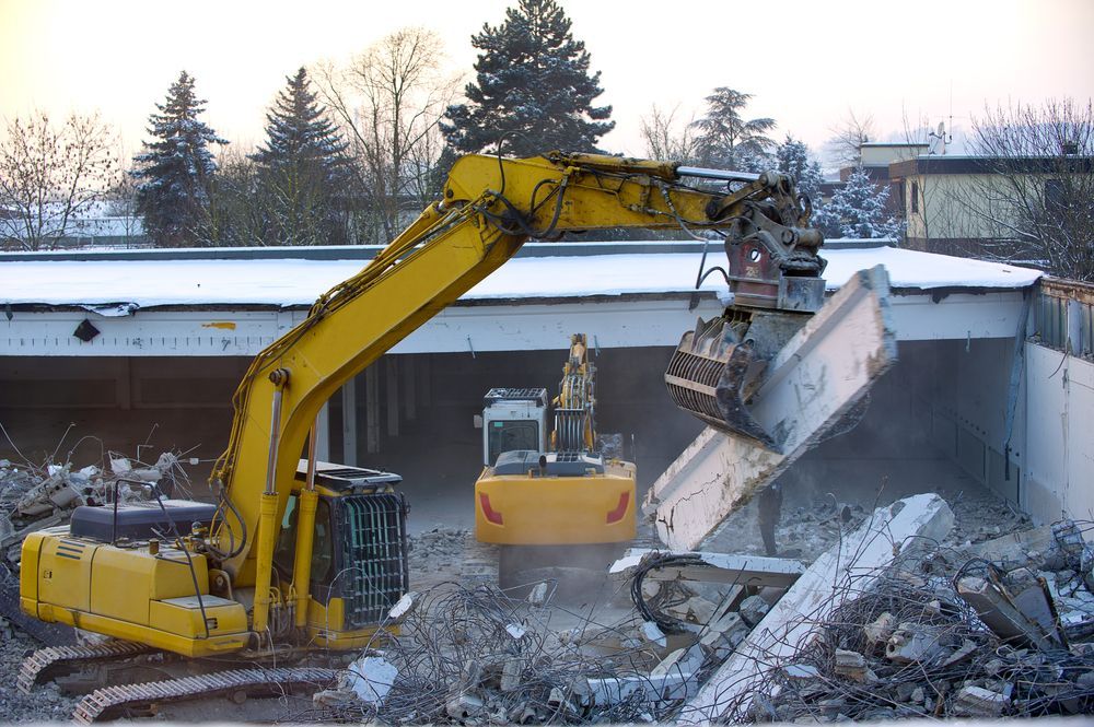 a yellow excavator performing a commercial demolition project.