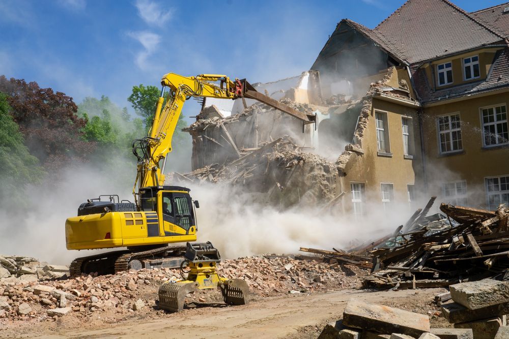 A large yellow excavator is demolishing a building.