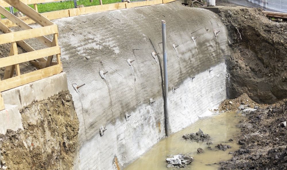 A large concrete wall is being built next to a large hole in the ground.