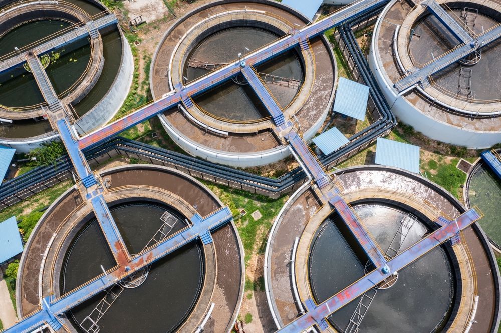 Aerial view of a wastewater treatment plant with multiple circular tanks and connecting walkways.