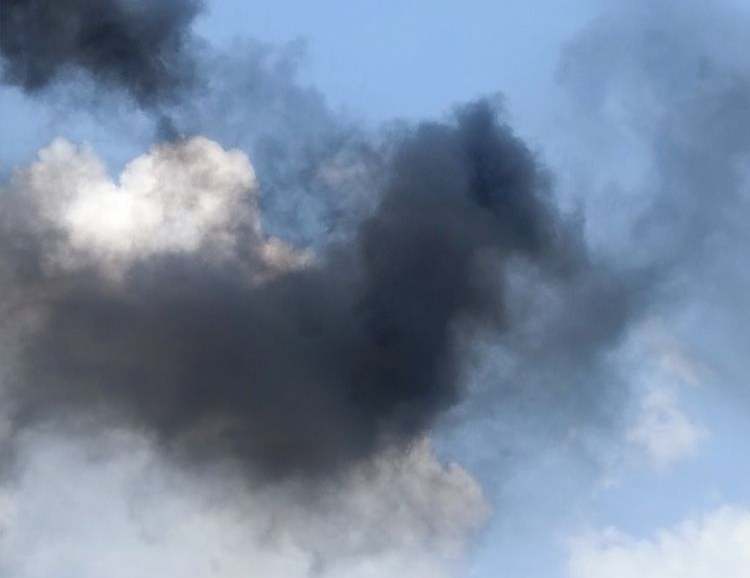 Close-up of dramatic sky with dark smoke-filled clouds and lighter cumulus clouds representing air monitoring conditions during demolition