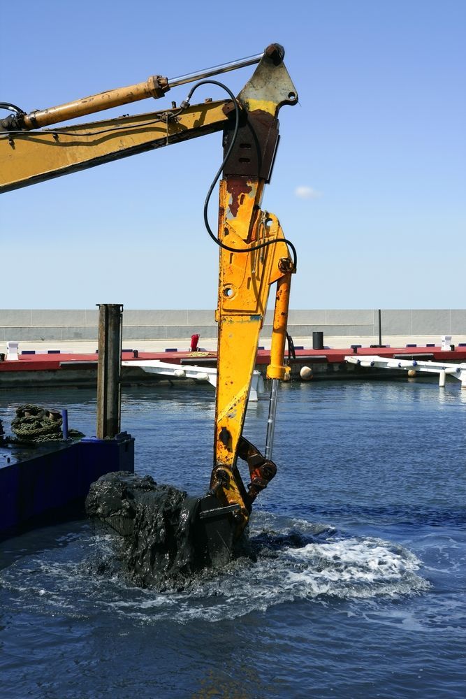 a yellow excavator is dredging a hole.