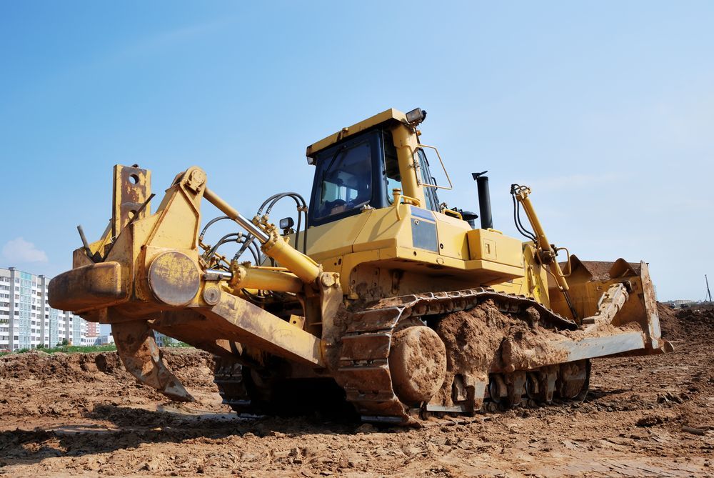 a yellow bulldozer is sitting on top of a dirt field.