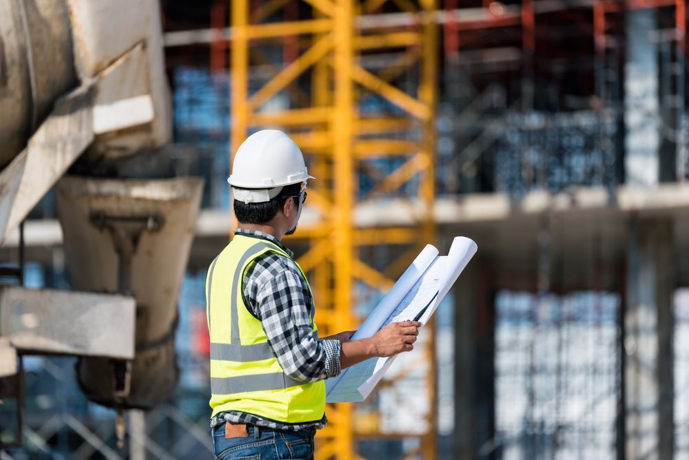 a construction worker is looking at a blueprint at a construction site, deciding on the demolition plan.