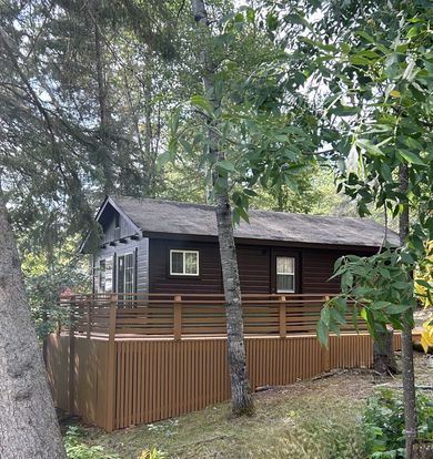 a green house is surrounded by trees in the middle of a forest .