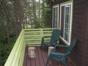 there are two chairs on the deck of a house .