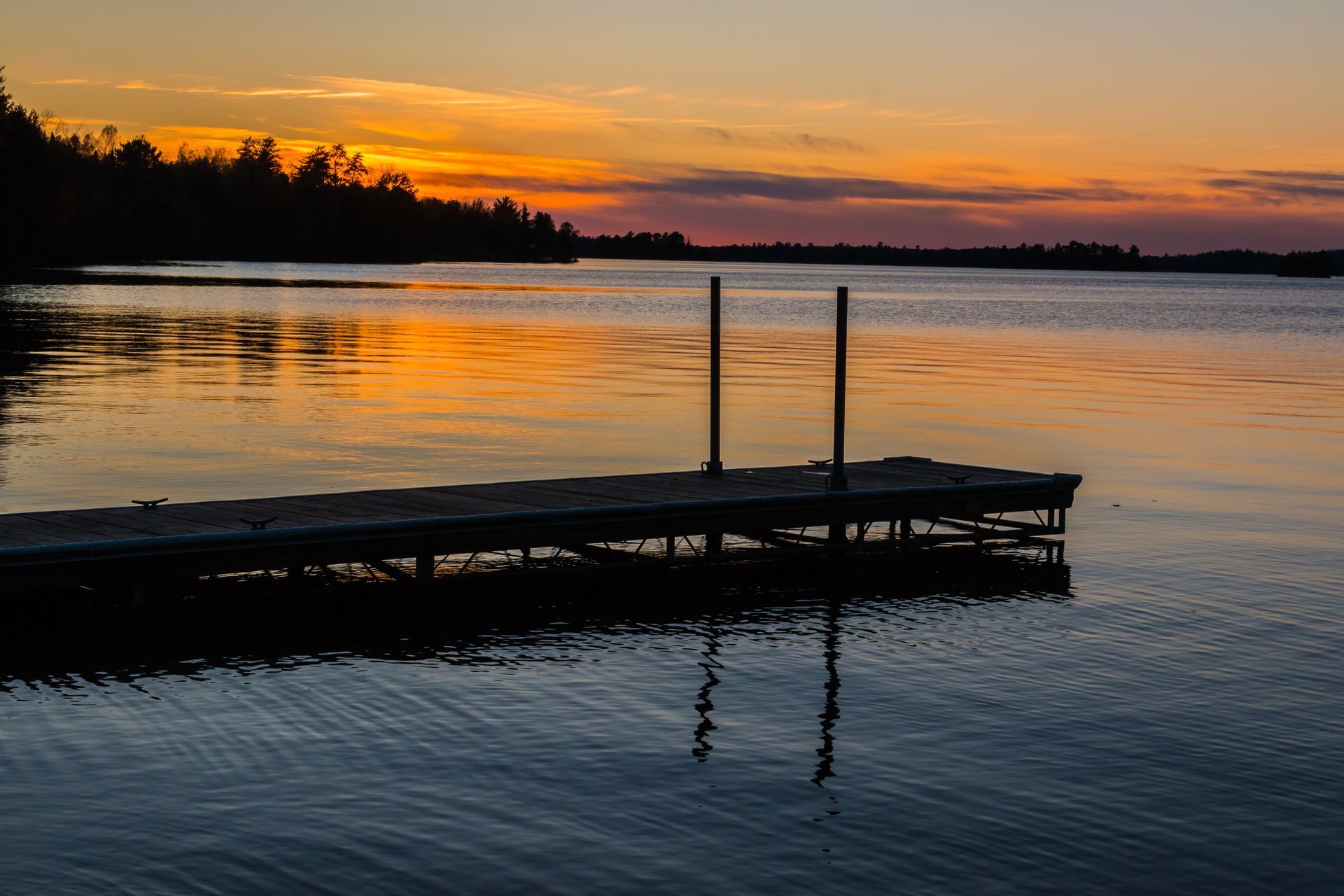 a dock in the middle of a lake at sunset .