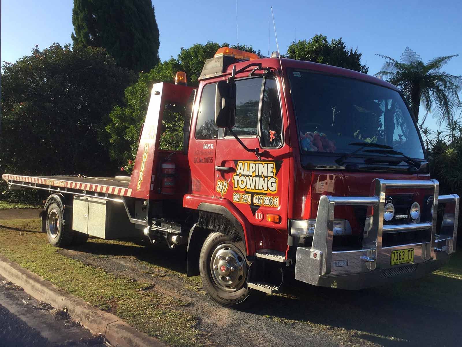 A Red Towing Truck Is Parked On Garden Area — Alpine Towing Services in Byron Bay NSW