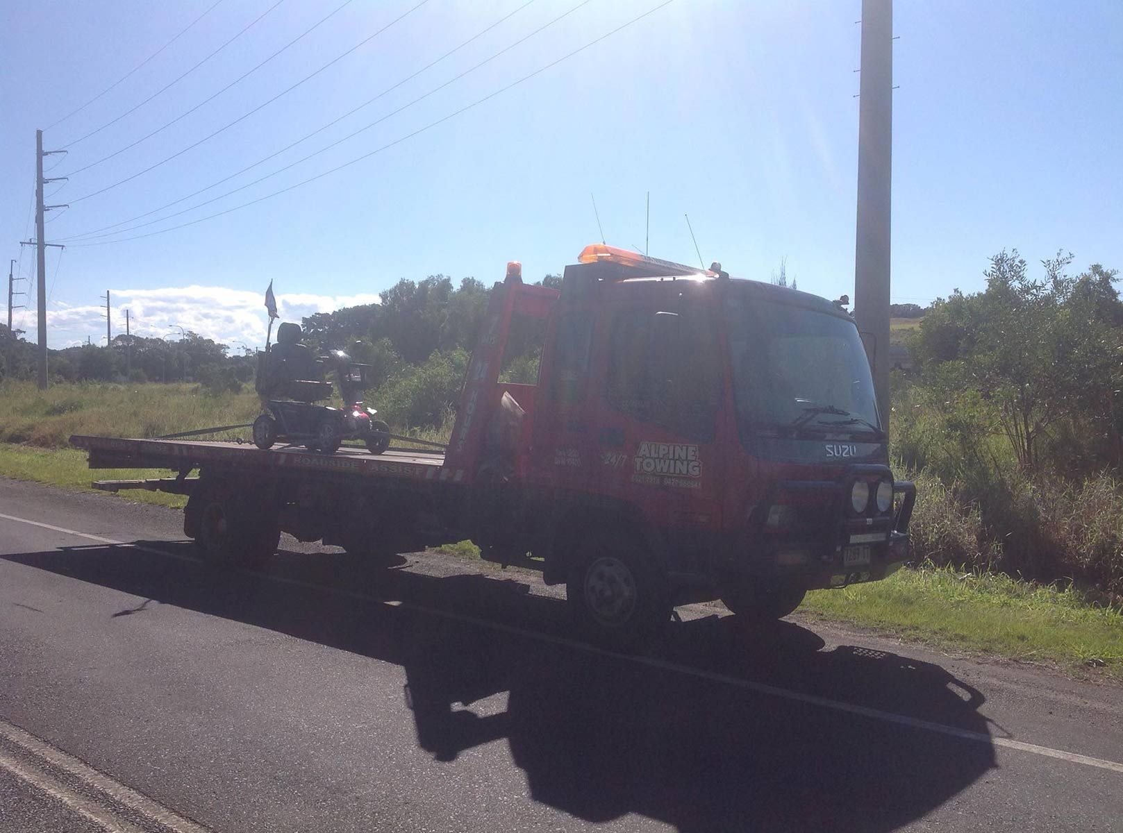 A Red Tow Truck Is Parked While Towing a Smart Car — Alpine Towing Services in Byron Bay NSW