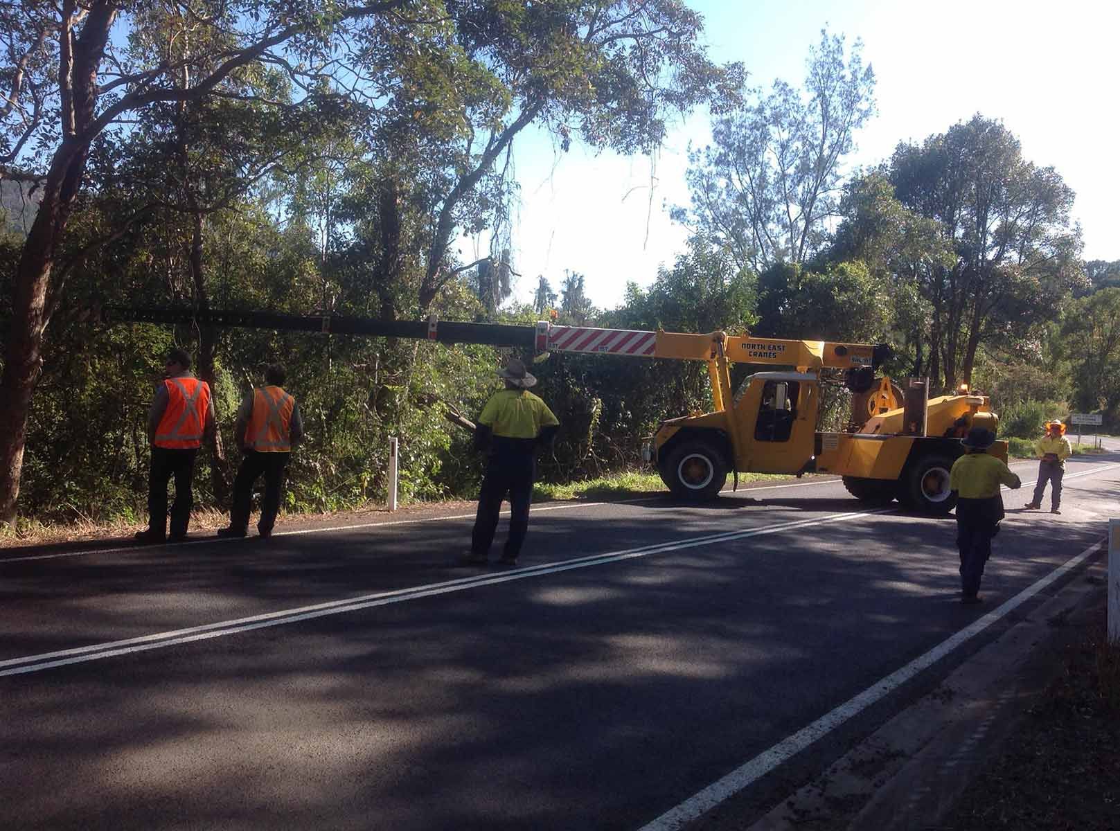 A Yellow Crane Is Lifting A Crashed Car From Road Side Valley — Alpine Towing Services in Byron Bay, NSW