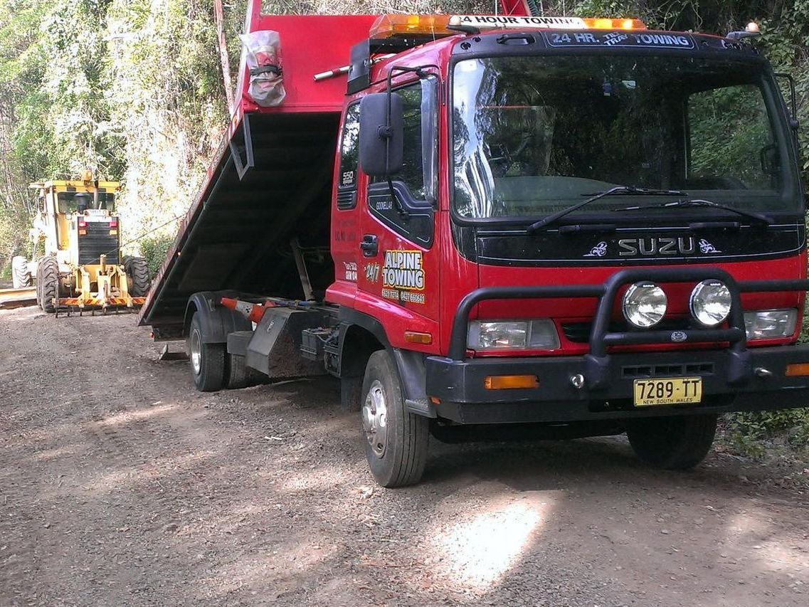 A Red Tow Truck Towing An Agricultural Machine — Alpine Towing Services in Lismore, NSW
