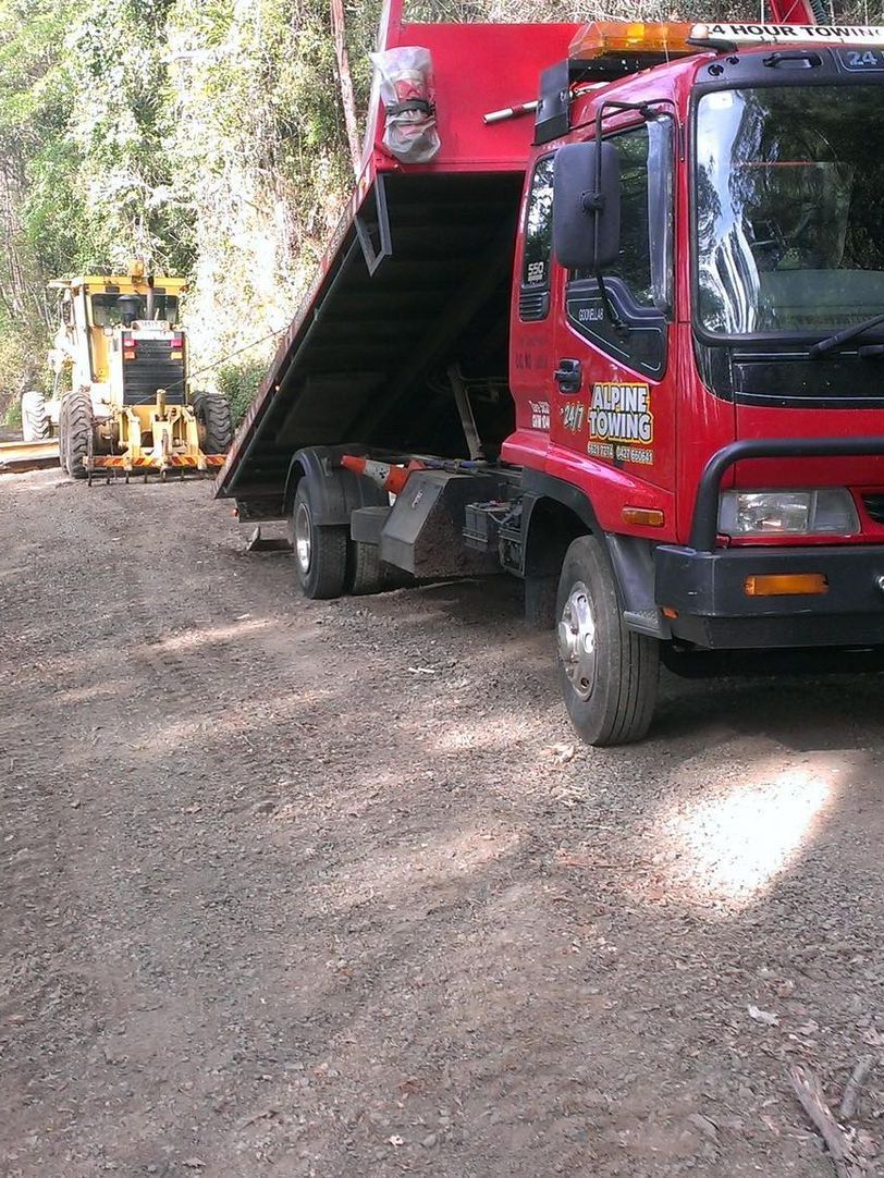 A Red Tow Truck Towing A Yellow Agricultural Grader — Alpine Towing Services in Lismore, NSW
