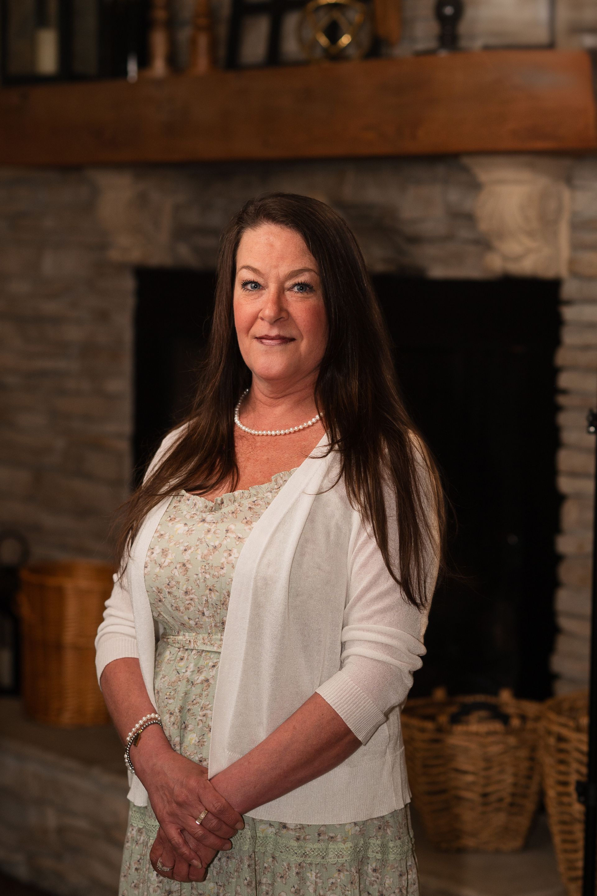 A woman is standing in front of a fireplace in a living room.