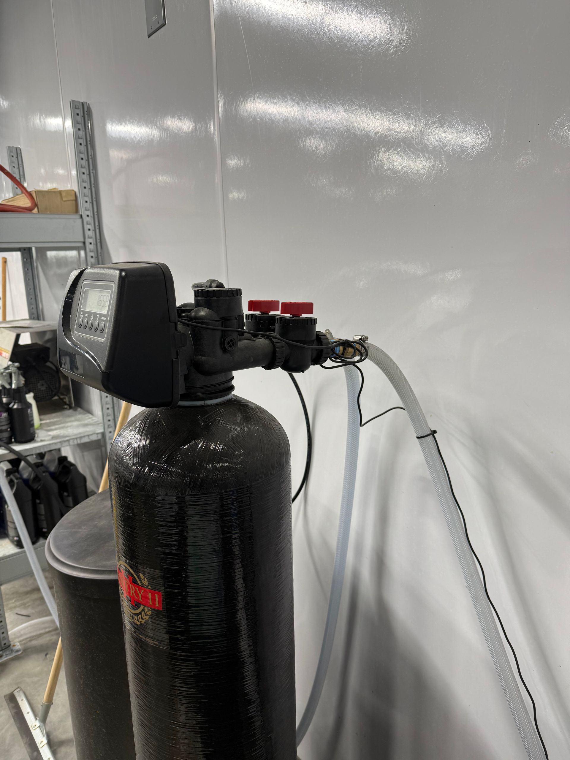 Improper installation of water softener using hose clamps and hose instead of proper pipe.