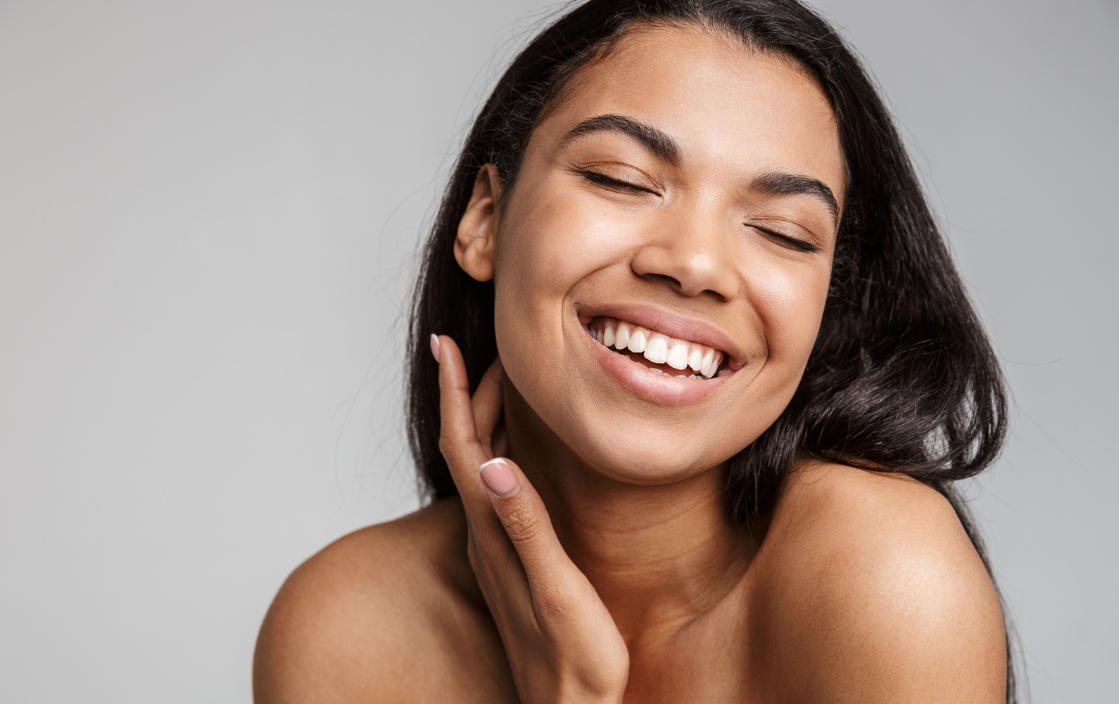 A woman is looking at her face in a mirror.