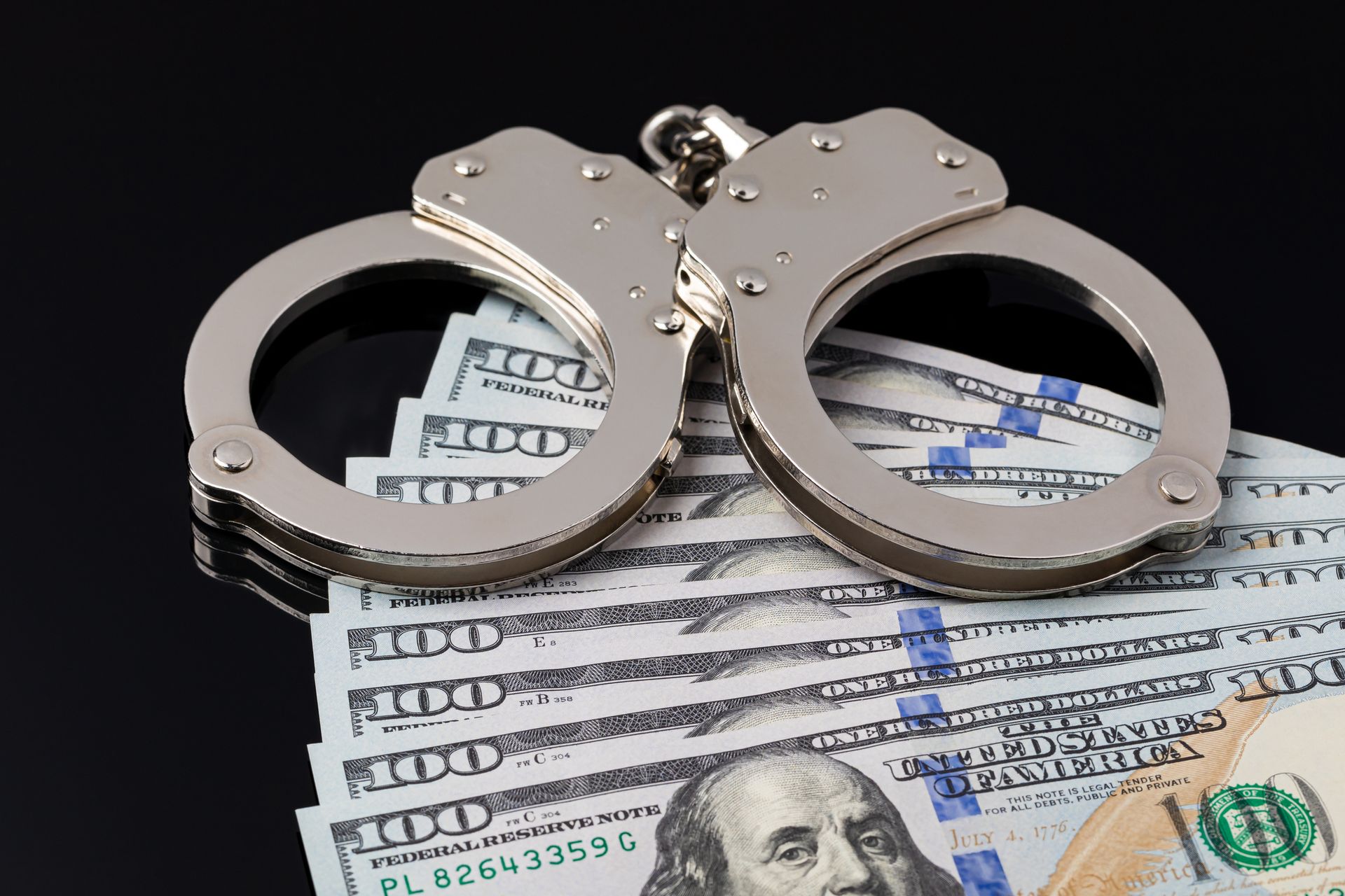 Handcuffs with cash money isolated on a black background.