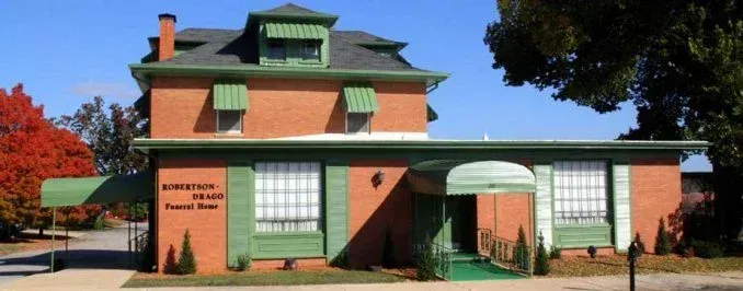 Robertson-Drago Funeral Home: a two-story brick building with green trim, awnings, and an entrance with a ramp.