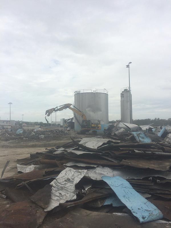 A pile of scrap metal is sitting in front of a large tank.